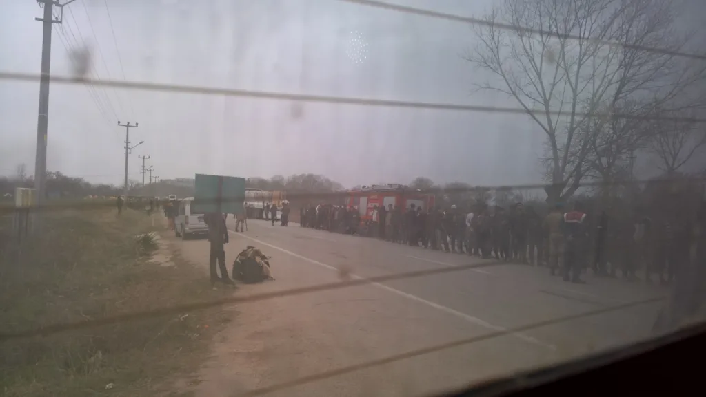Migrants waiting in line as seen from inside a police car