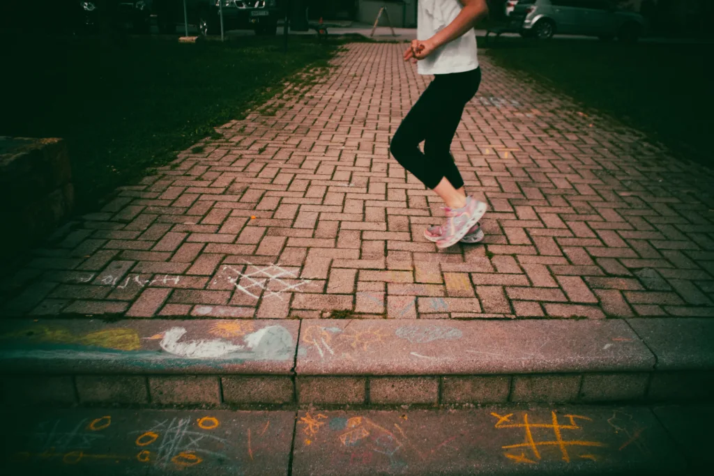 This delightful photograph captures a young girl immersed in play, surrounded by vibrant chalk drawings in a park. She enthusiastically engages with the colorful artwork, allowing her imagination to roam freely. The lively and creative atmosphere of the park is evident as the chalk drawings bring the space to life with their vivid hues and imaginative designs. This image encapsulates the spirit of childhood, highlighting the joy, innocence, and boundless imagination that can be found in simple moments of play.